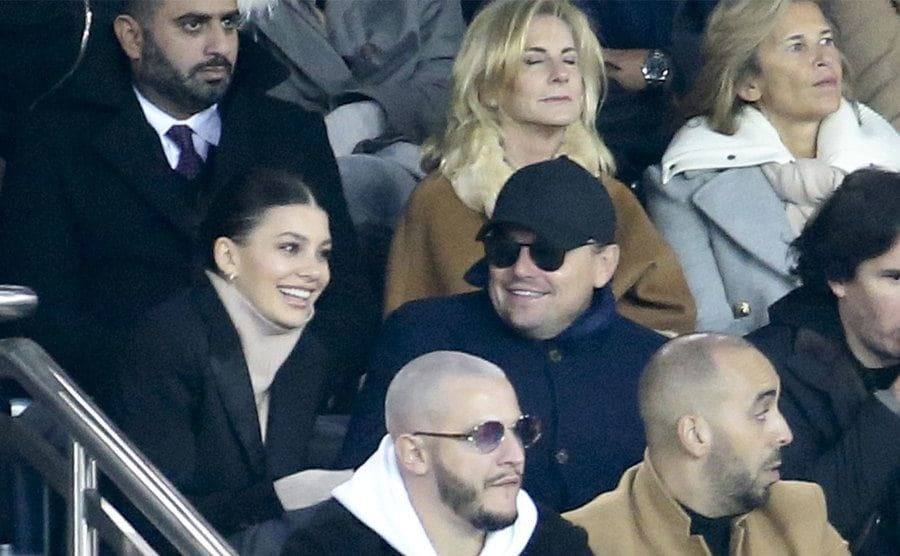 Leonardo DiCaprio and Camila Morrone watch a game. 