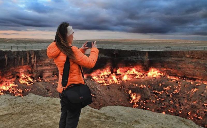 A woman takes a photo of the “Gates of Hell”. 