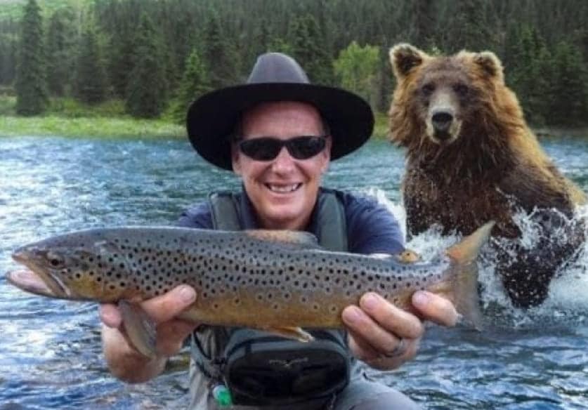 A man holding a fish in front of a bear