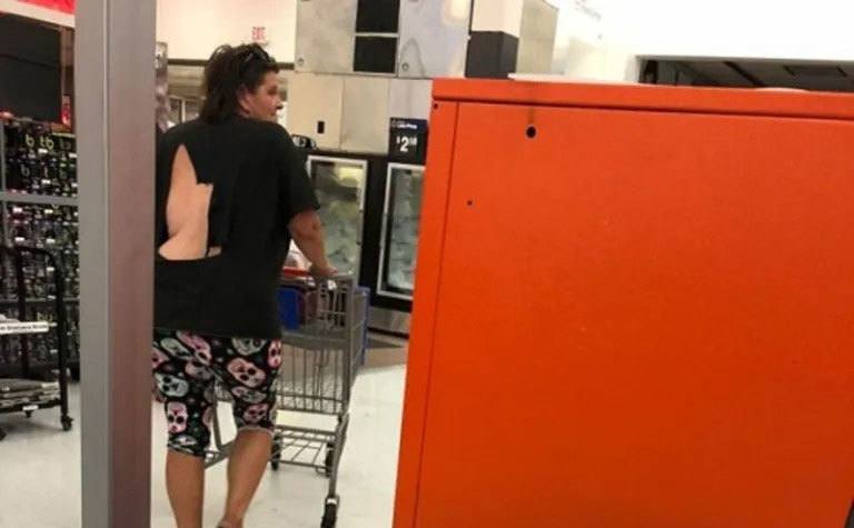 A woman walks through the store with a massive tear on the back of her shirt