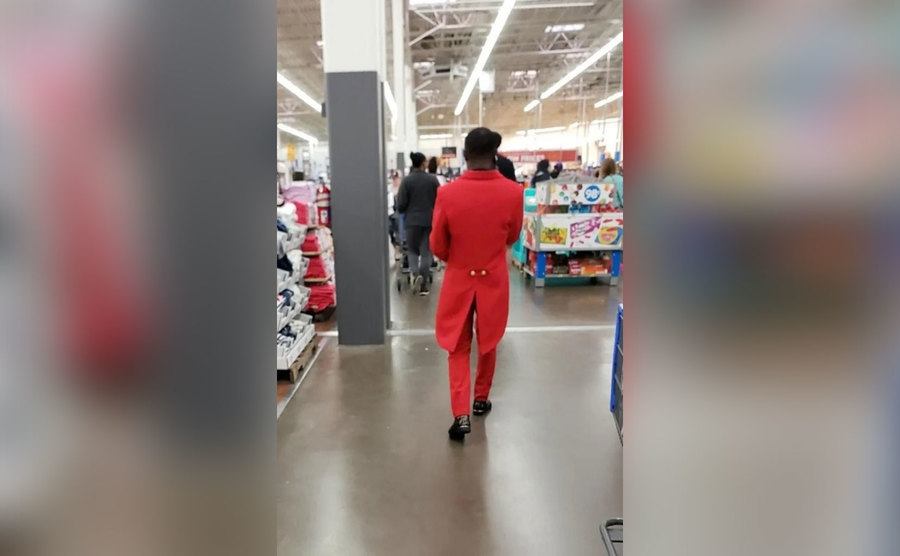 A man shops in a red suit with coattails. 