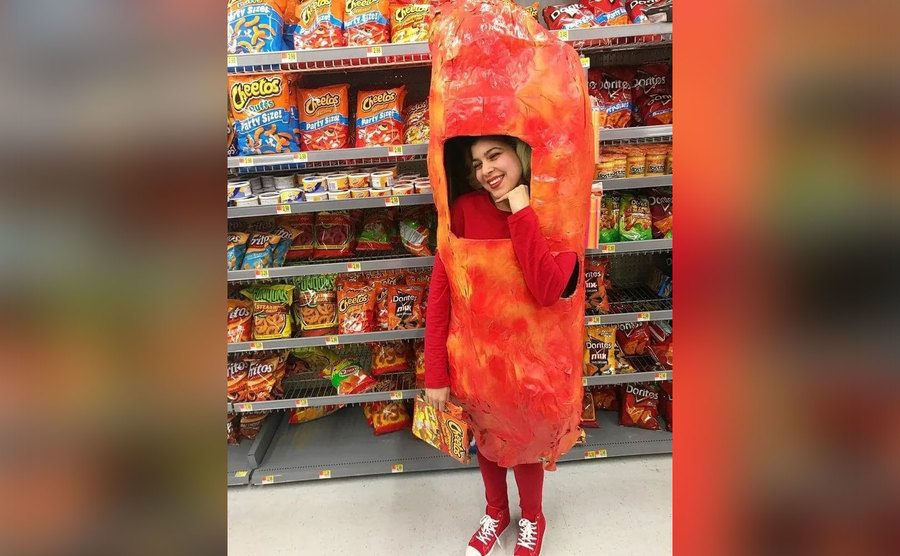 A woman dressed as a flaming hot Cheeto poses in the store. 
