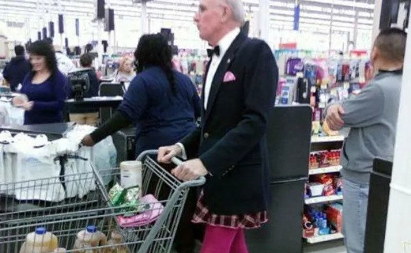 A man shops in a suit jacket, plaid skirt, and hot pink tights. 
