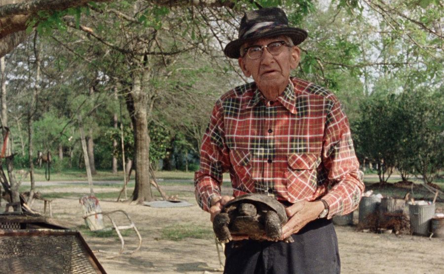 A man holds up a Gopher Tortoise. 
