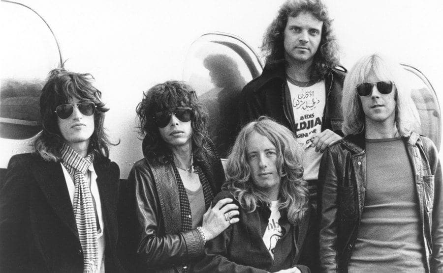Aerosmith poses for a portrait in front of their plane. 