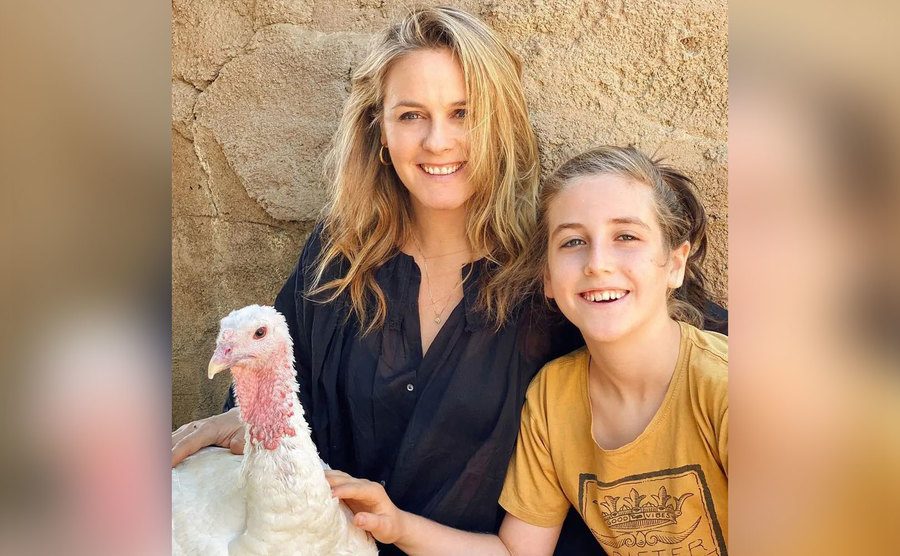 Alicia and her son pet a turkey. 